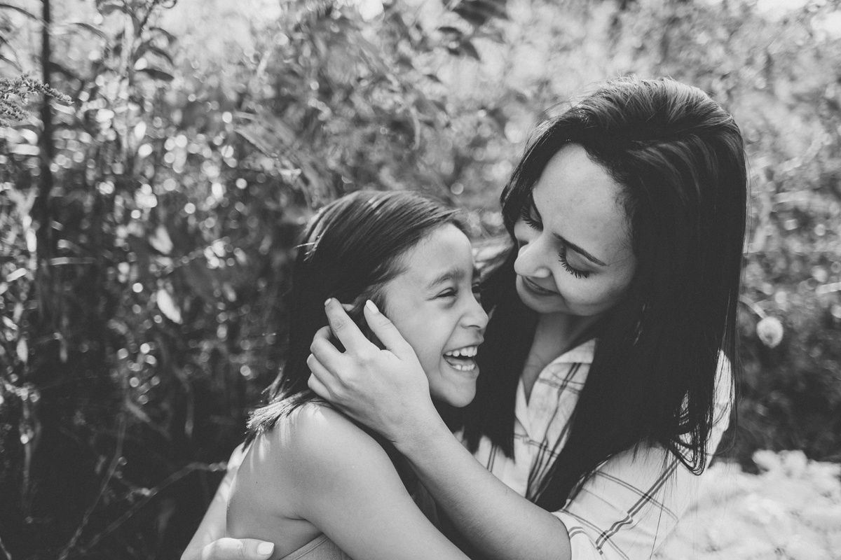 Black and white portrait of two people sharing laughter and embrace outdoors.