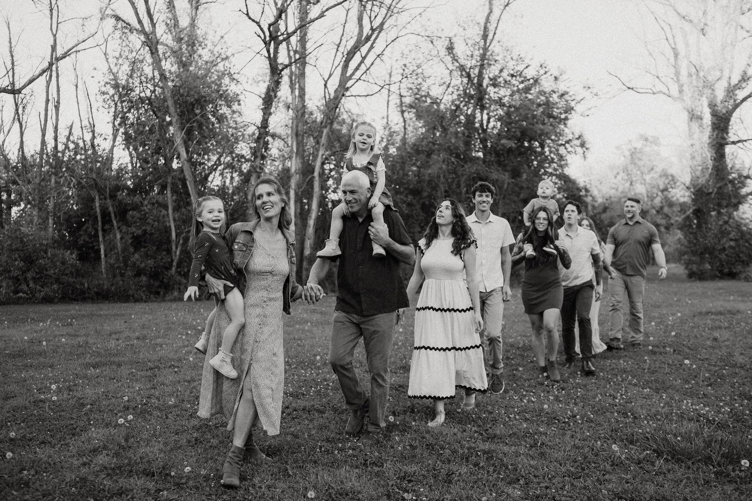 Black and white photograph of group gathering outdoors among trees.