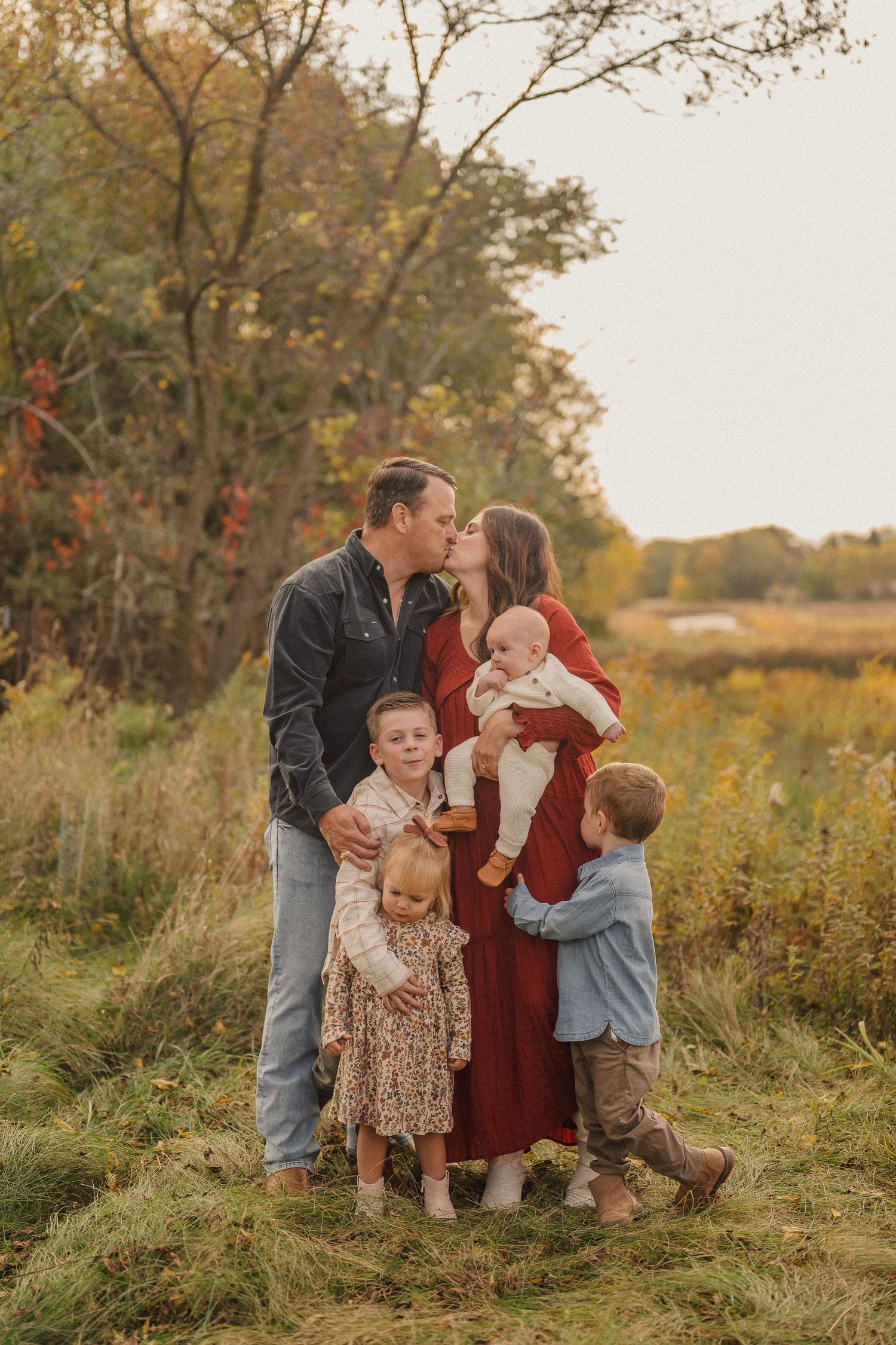 Candid family moment captured in a natural setting with autumn colors and tall grass.