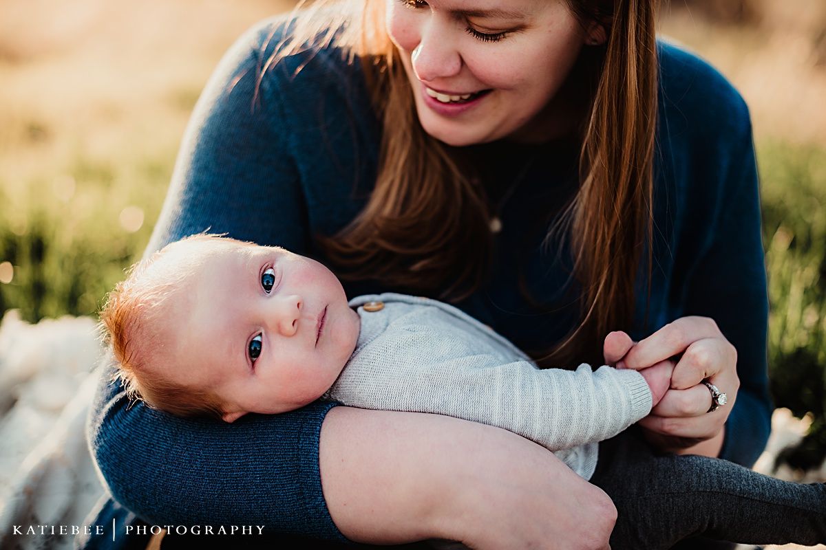 A sweet candid moment of parent and baby bonding outdoors at sunset with natural lighting.
