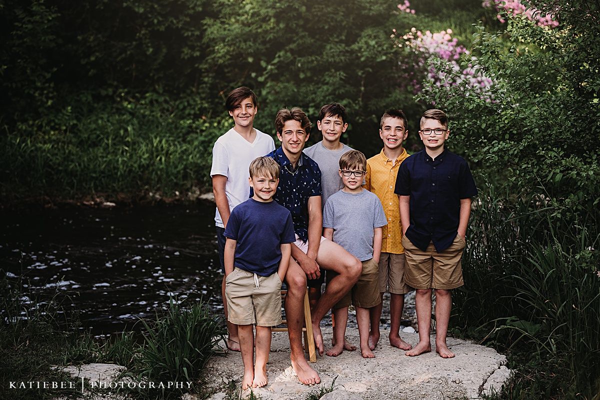 Group of young people standing together on rocky outcrop near water.