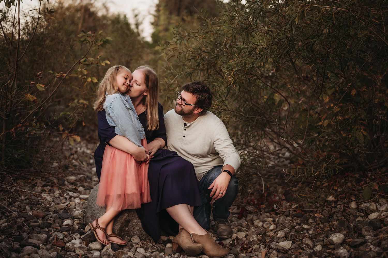 A family shares a tender moment together on rocky terrain at sunset.