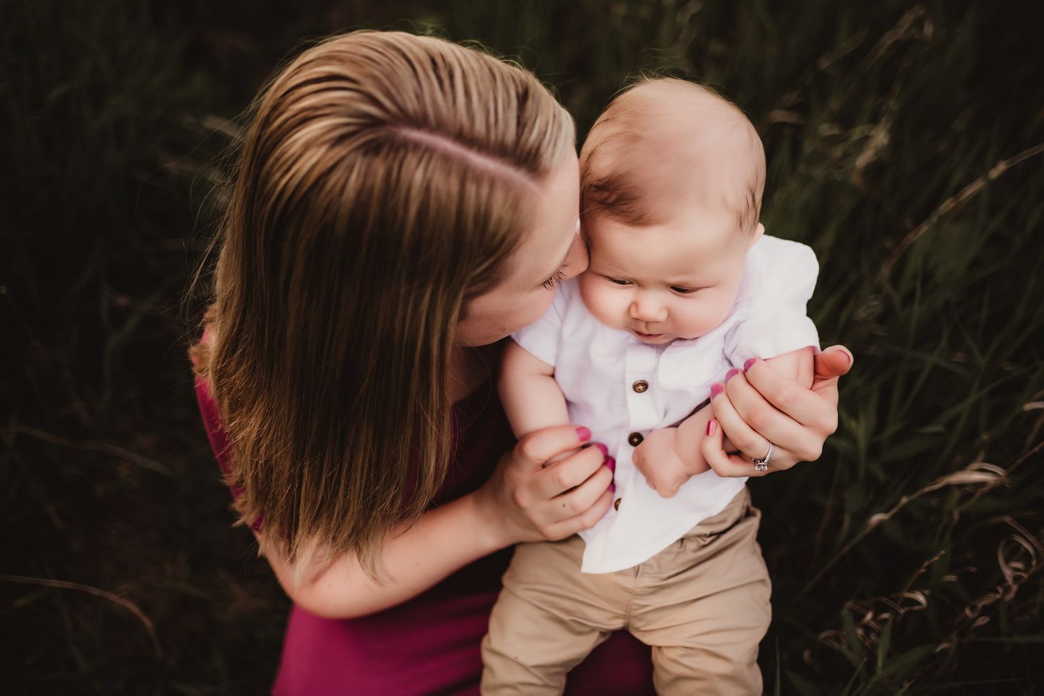 Tender outdoor portrait showing an embrace in burgundy against natural foliage.