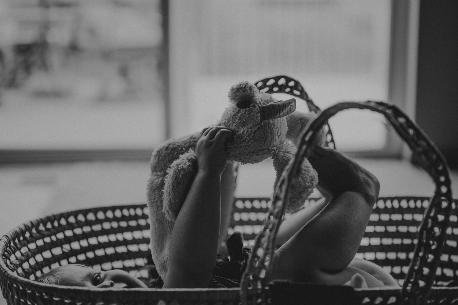 Black and white photo of baby feet in woven basket.