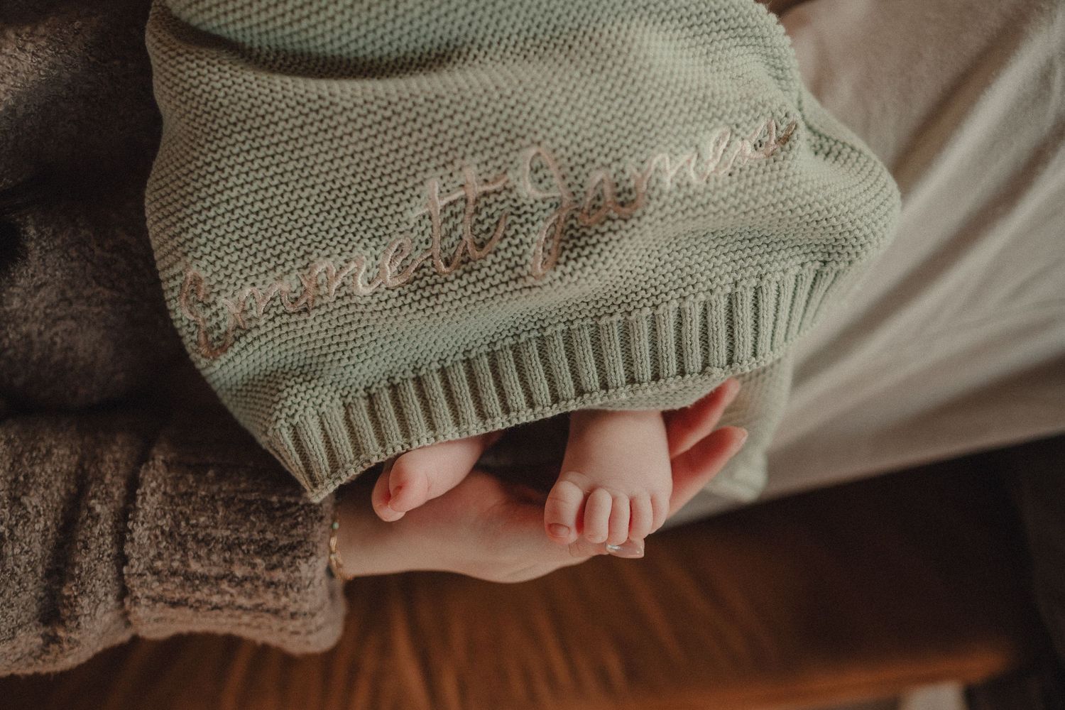 Close-up detail of knitted baby clothing and blankets in neutral earth tones.