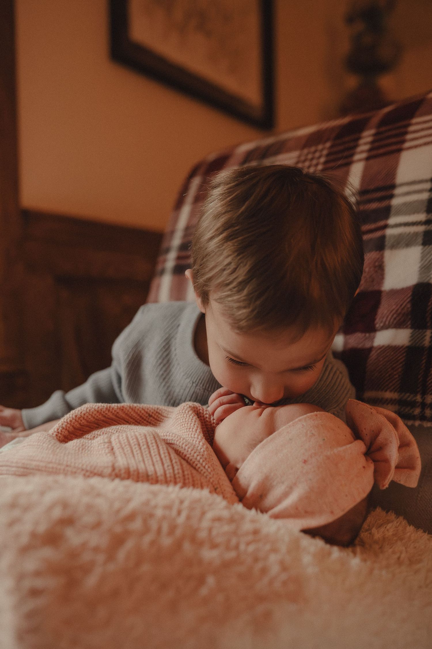 Warm-toned image of someone resting peacefully on plaid furniture in soft lighting.