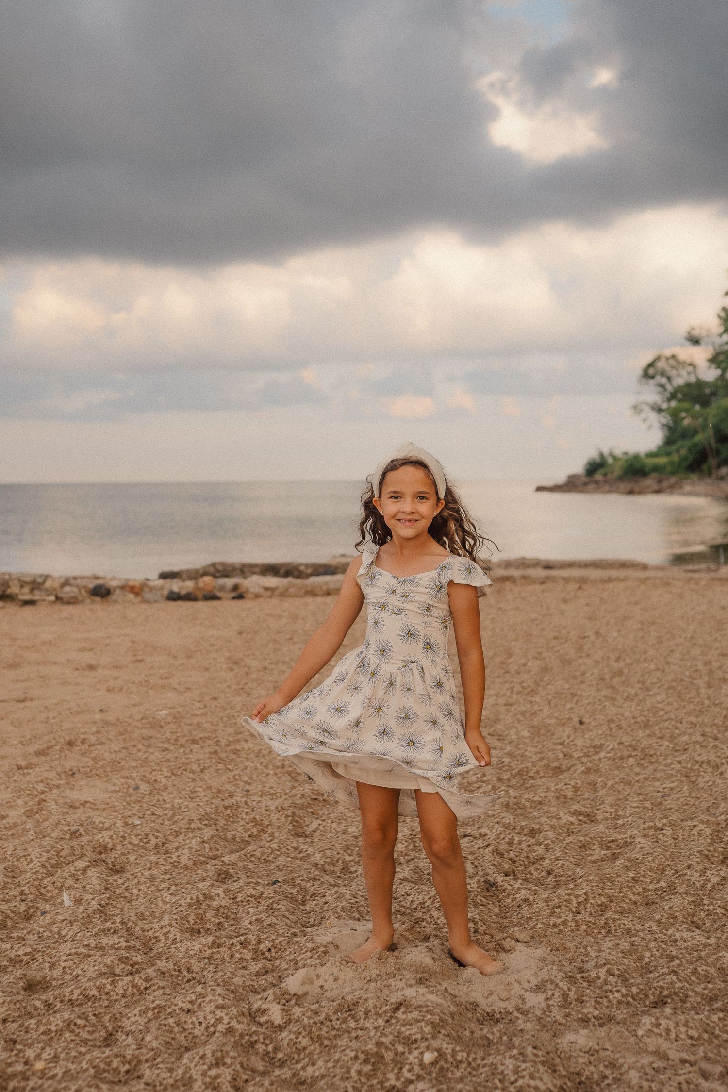 A dreamy sequence of photos shows a white dress twirling against a cloudy beach landscape at sunset.