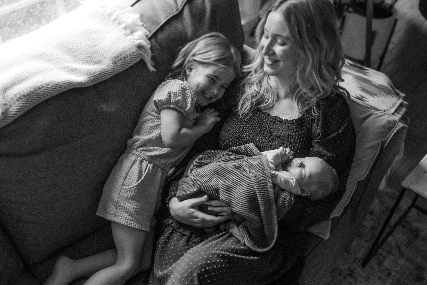 A peaceful black and white image of a family resting together on a couch.