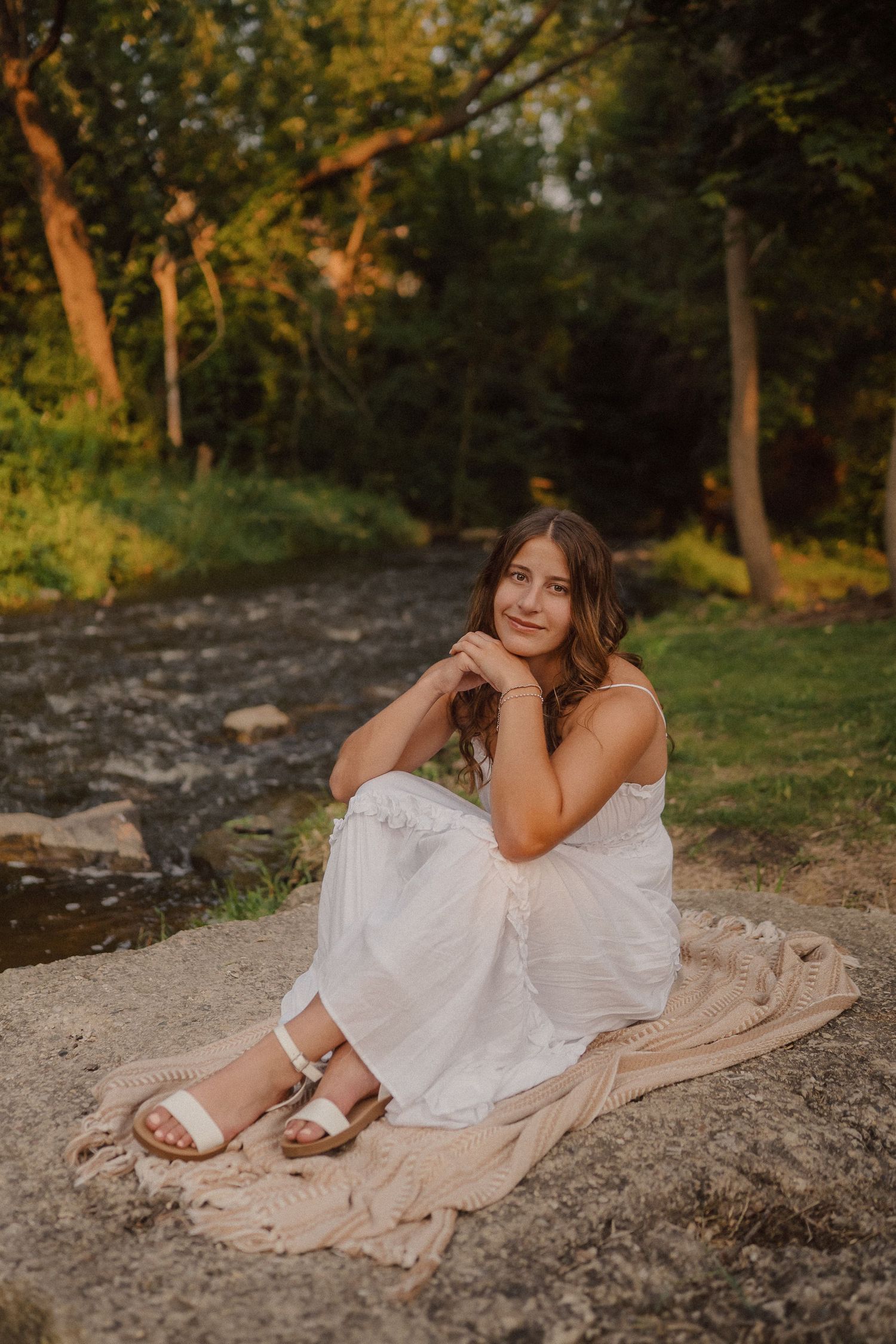 Peaceful outdoor portrait on blanket by stream at sunset.