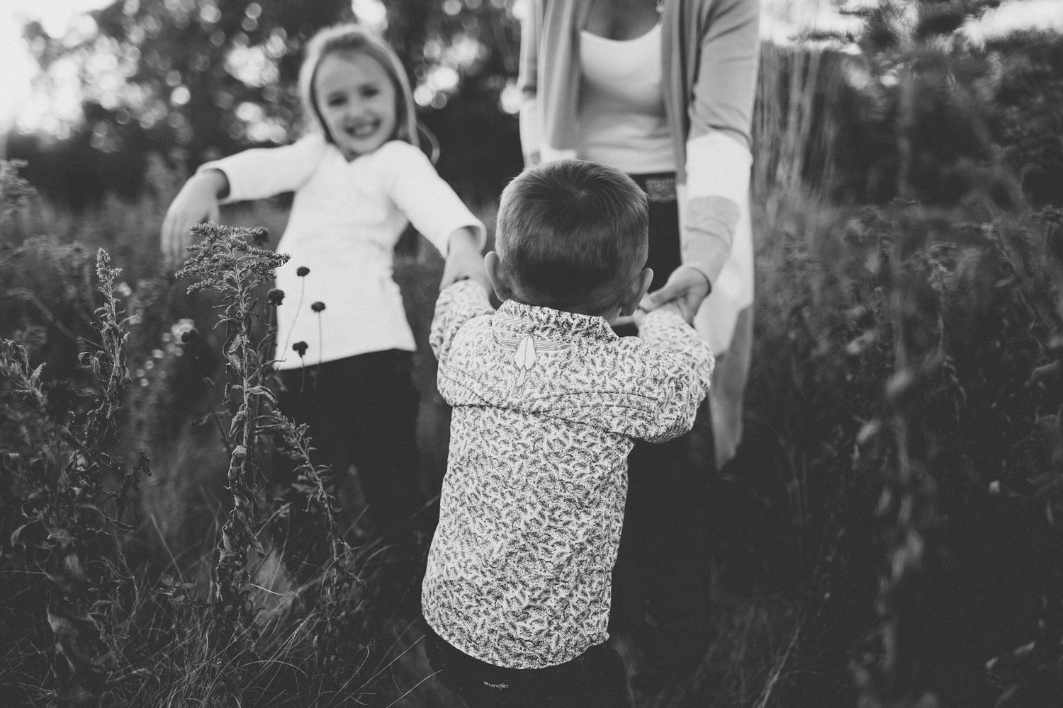 A candid black and white family scene of playtime in nature.