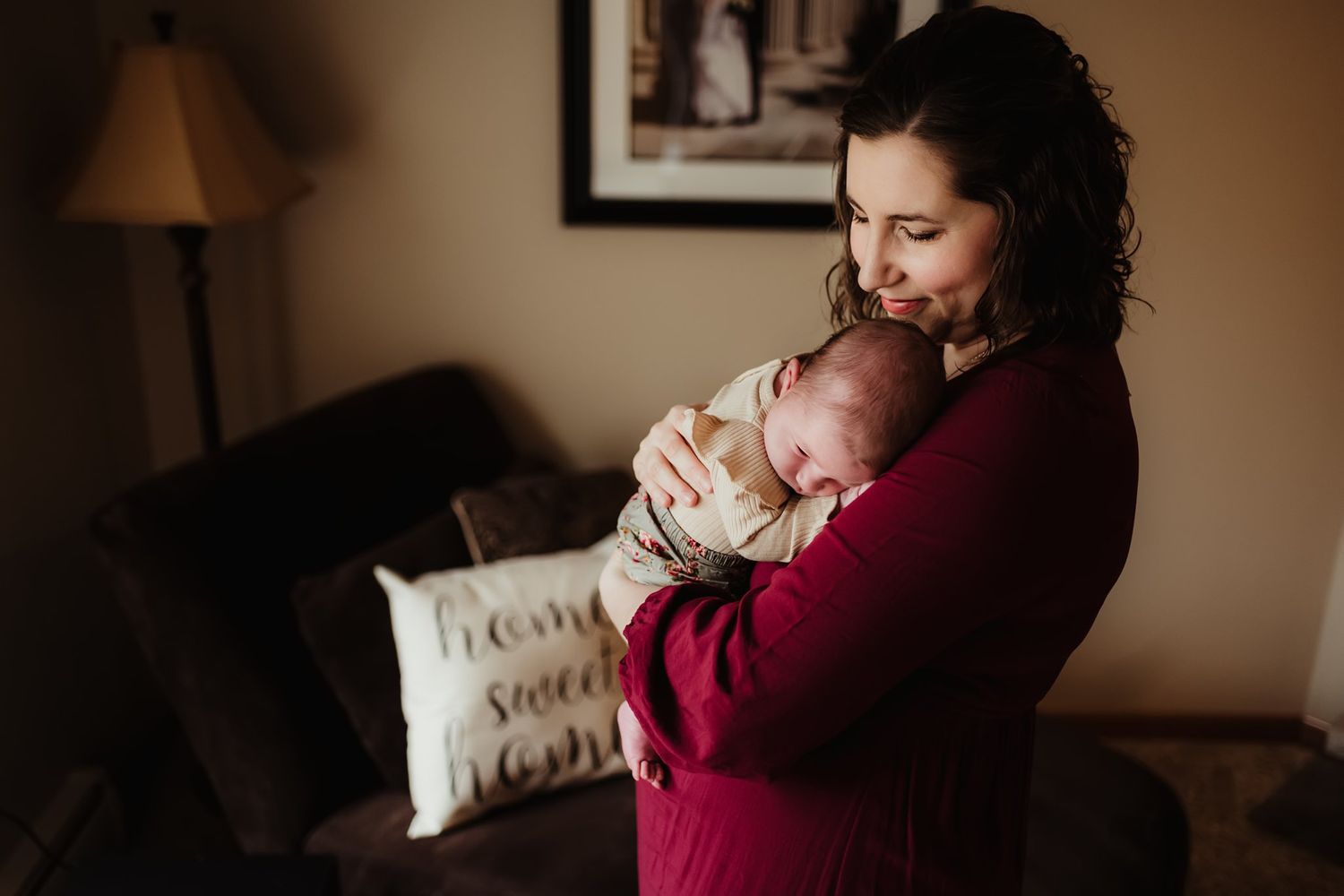 An intimate moment between a parent and newborn baby in a cozy living room setting.