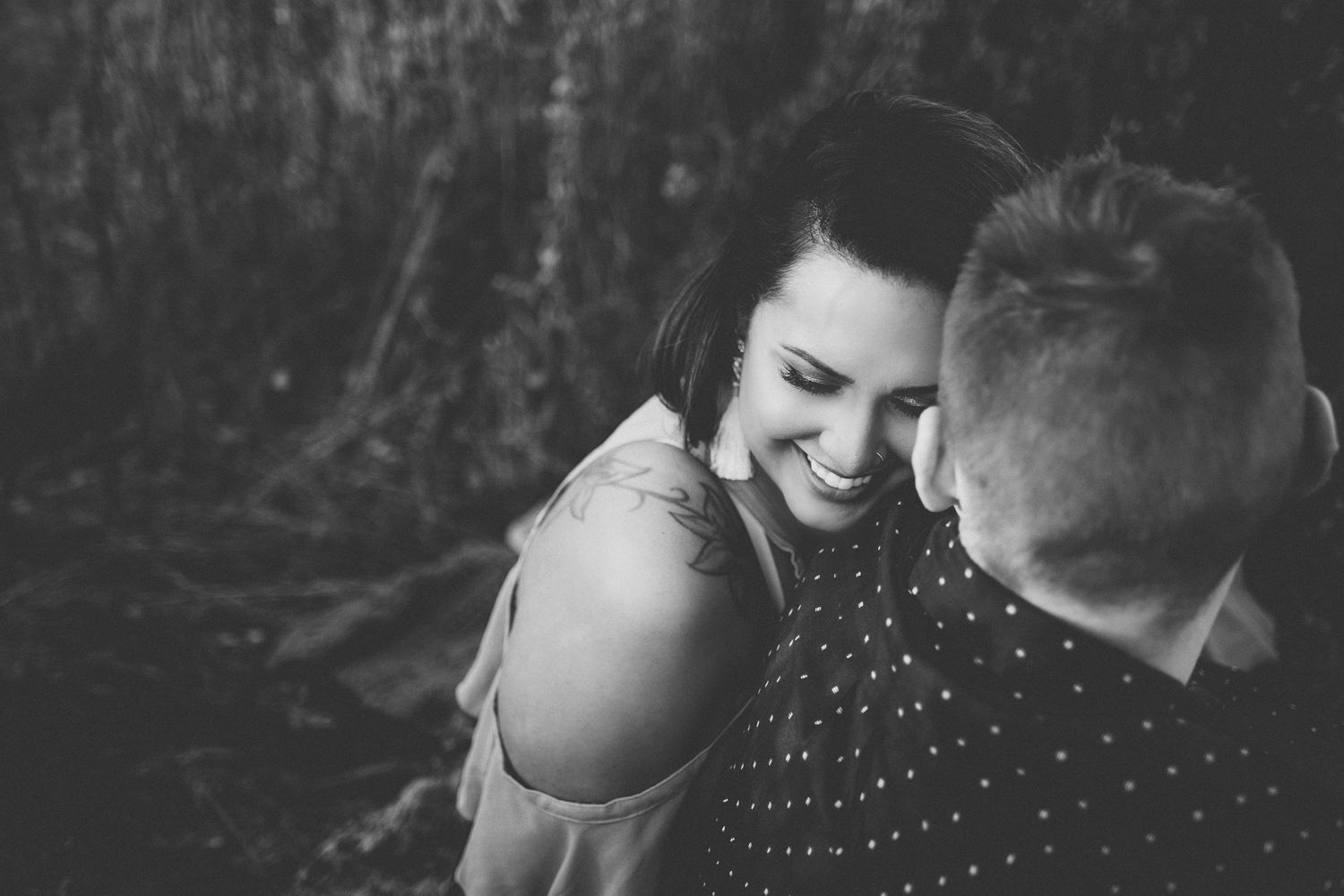 Black and white close-up portrait showing tender moment between couple outdoors.