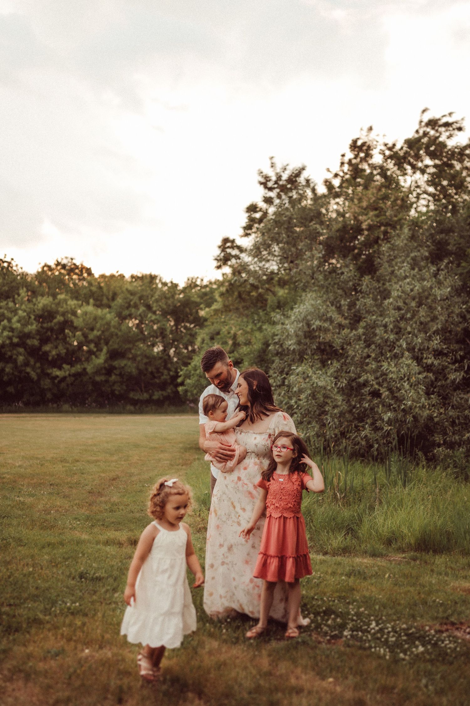 A family portrait in warm tones featuring natural outdoor scenery and flowing dresses.