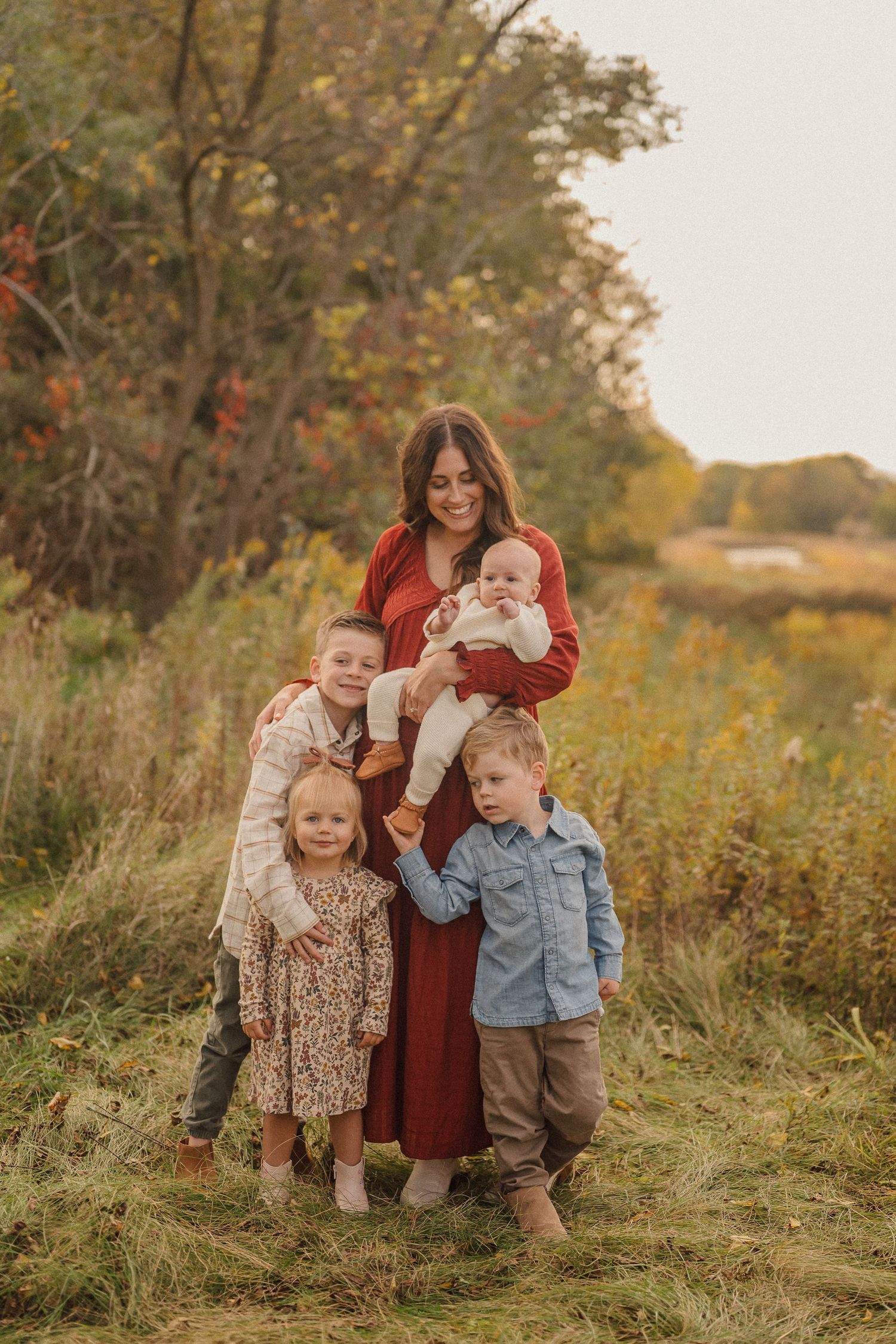 A family enjoys a playful moment together in a golden field during sunset.