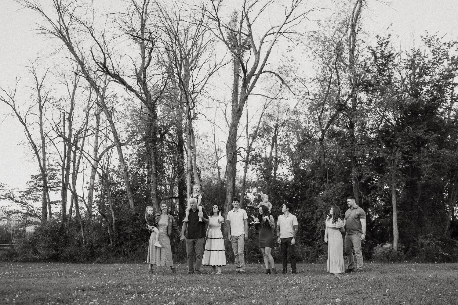 Black and white panoramic view of people gathered in a wooded clearing.