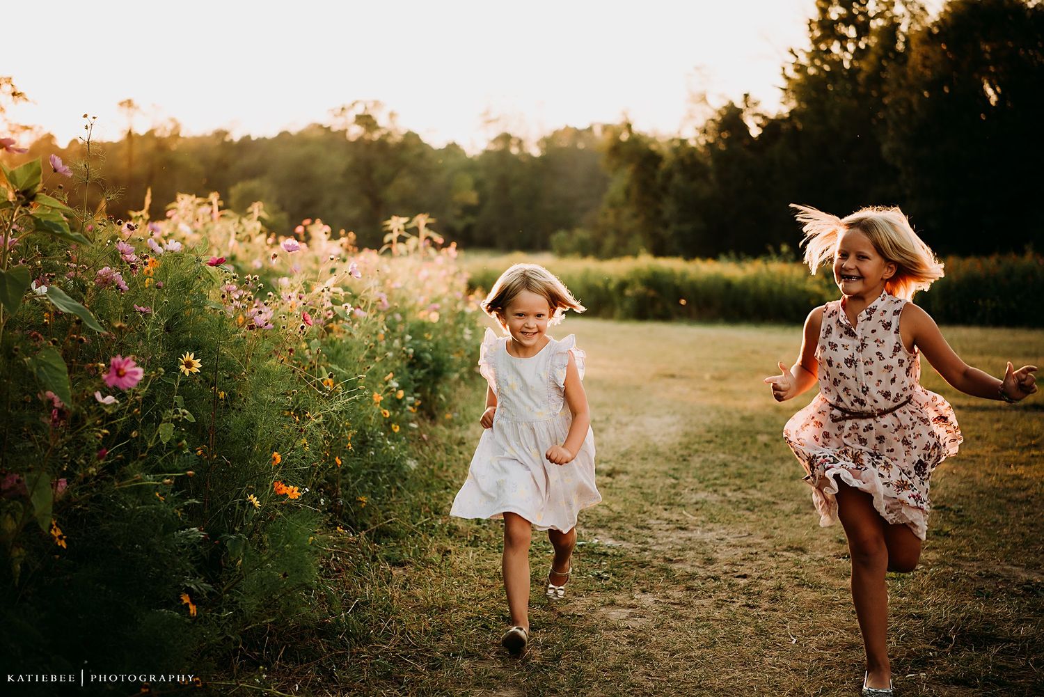 Two children running joyfully along a path bordered by wildflowers at sunset.