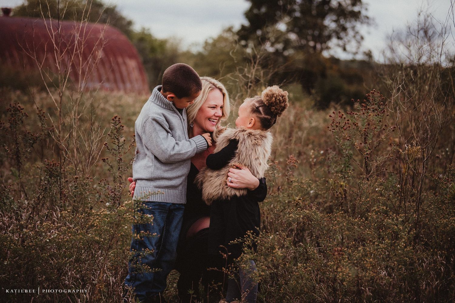 Intimate family photo showing playful interaction between loved ones in rustic outdoor setting.