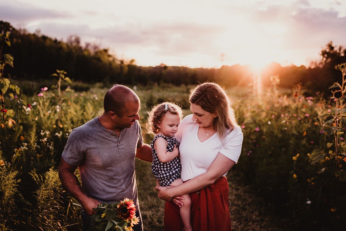 Family enjoying a sunset moment together in a wildflower field.