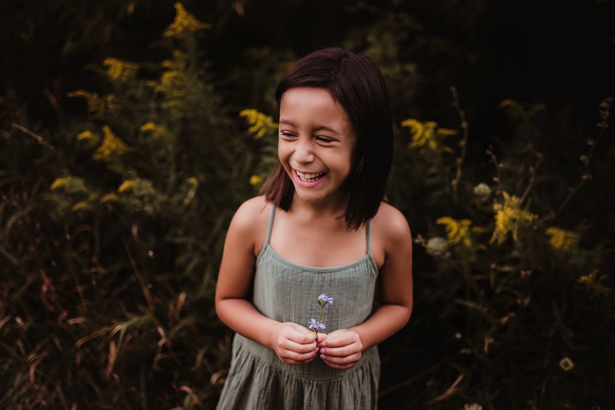 Natural light portrait showing genuine laughter against autumn foliage.