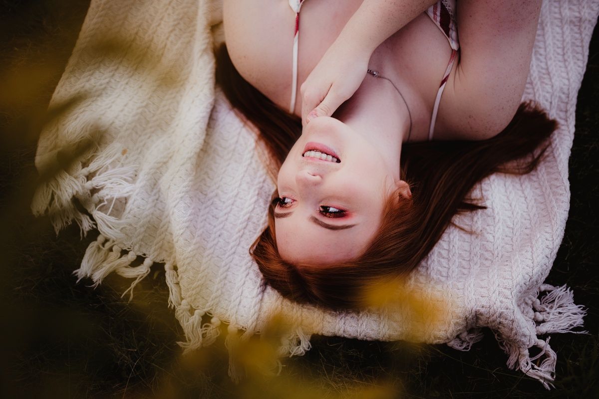 An artistic overhead portrait on white blanket with dramatic lighting.