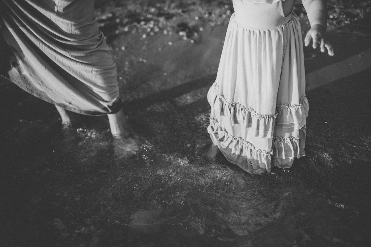 Black and white image of flowing dresses dipping into rippling water.