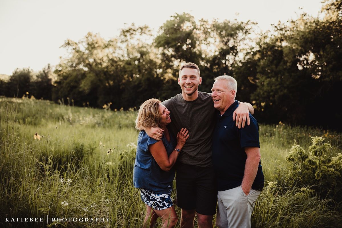 Three people posing together outdoors during sunset photography session.