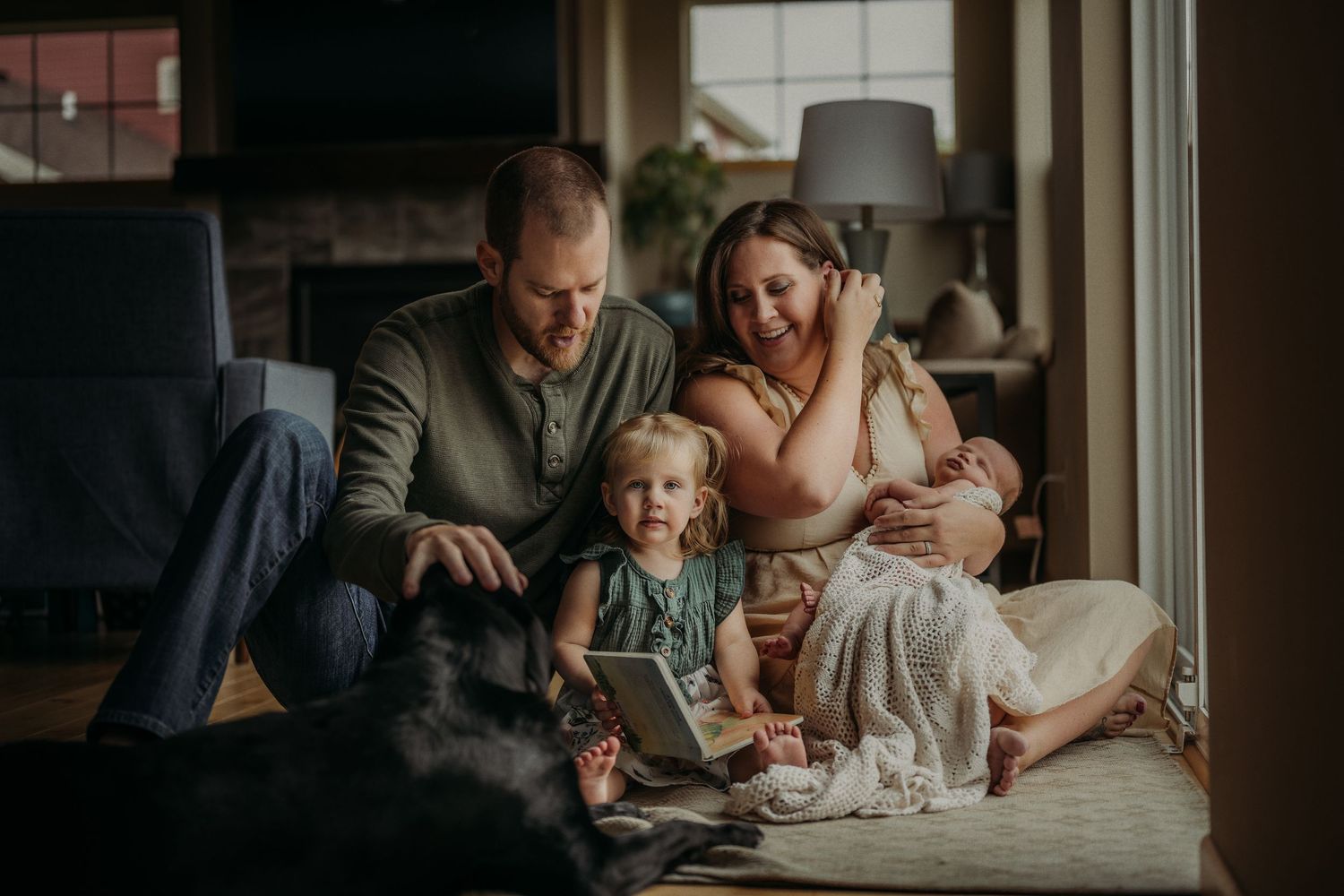 Cozy indoor family scene with dog and children gathered on floor near window.
