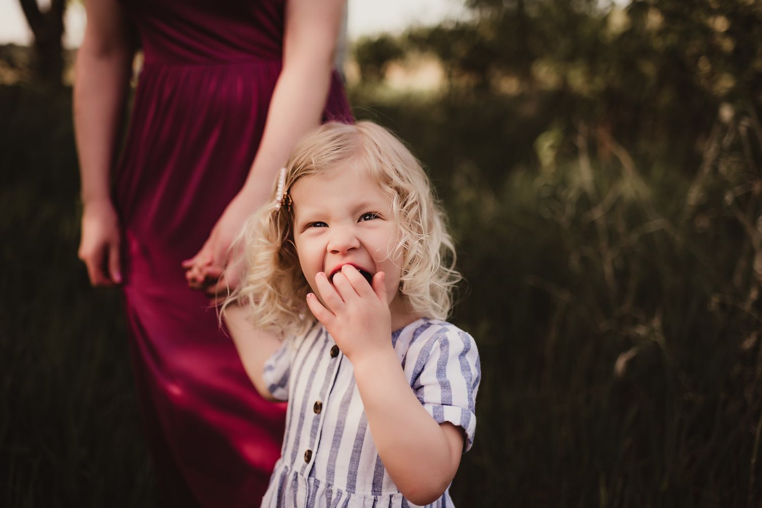 Candid moment of a laughing child in striped dress during outdoor photoshoot.