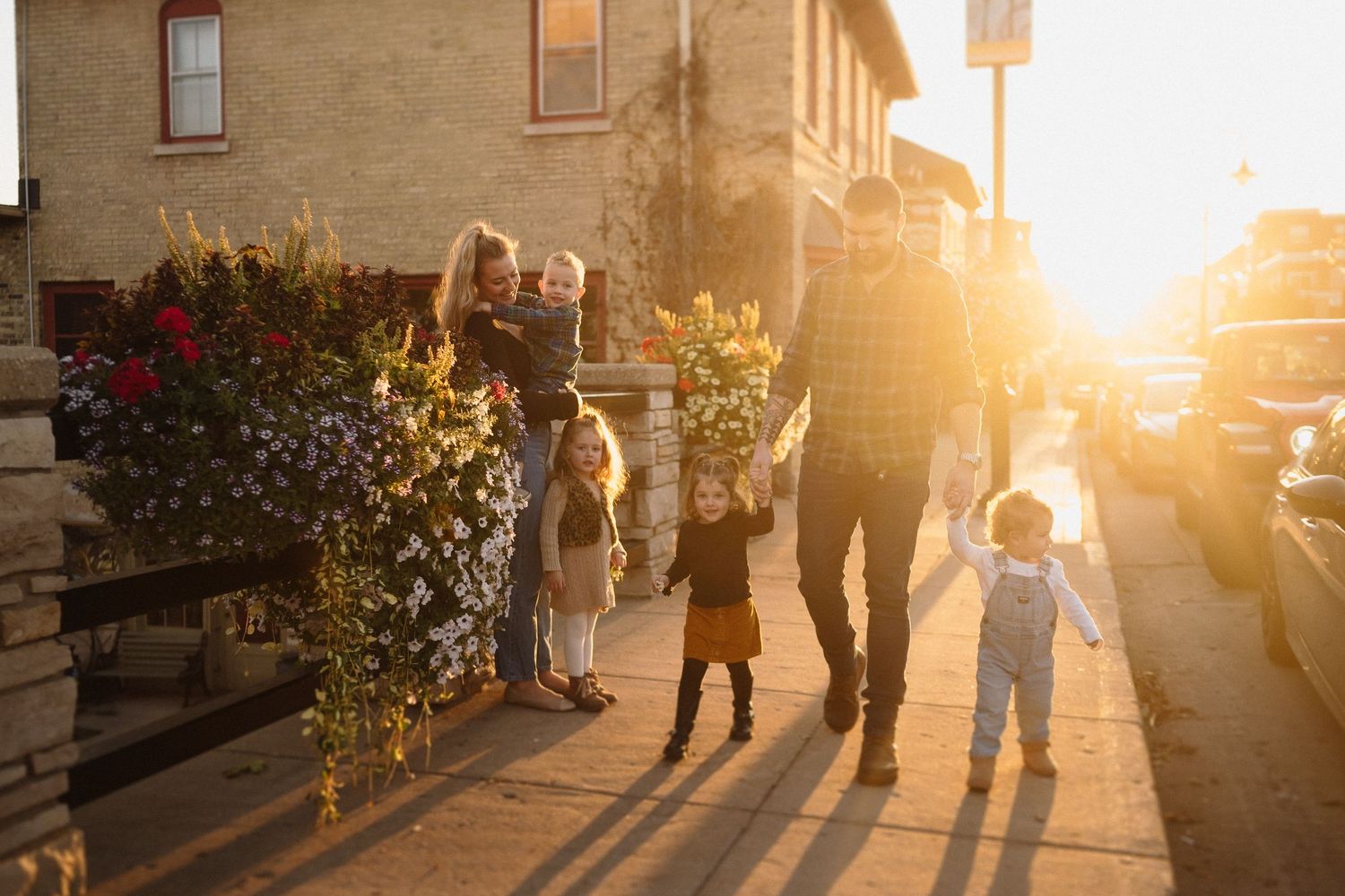 A family walks together at sunset with long shadows on a city sidewalk.