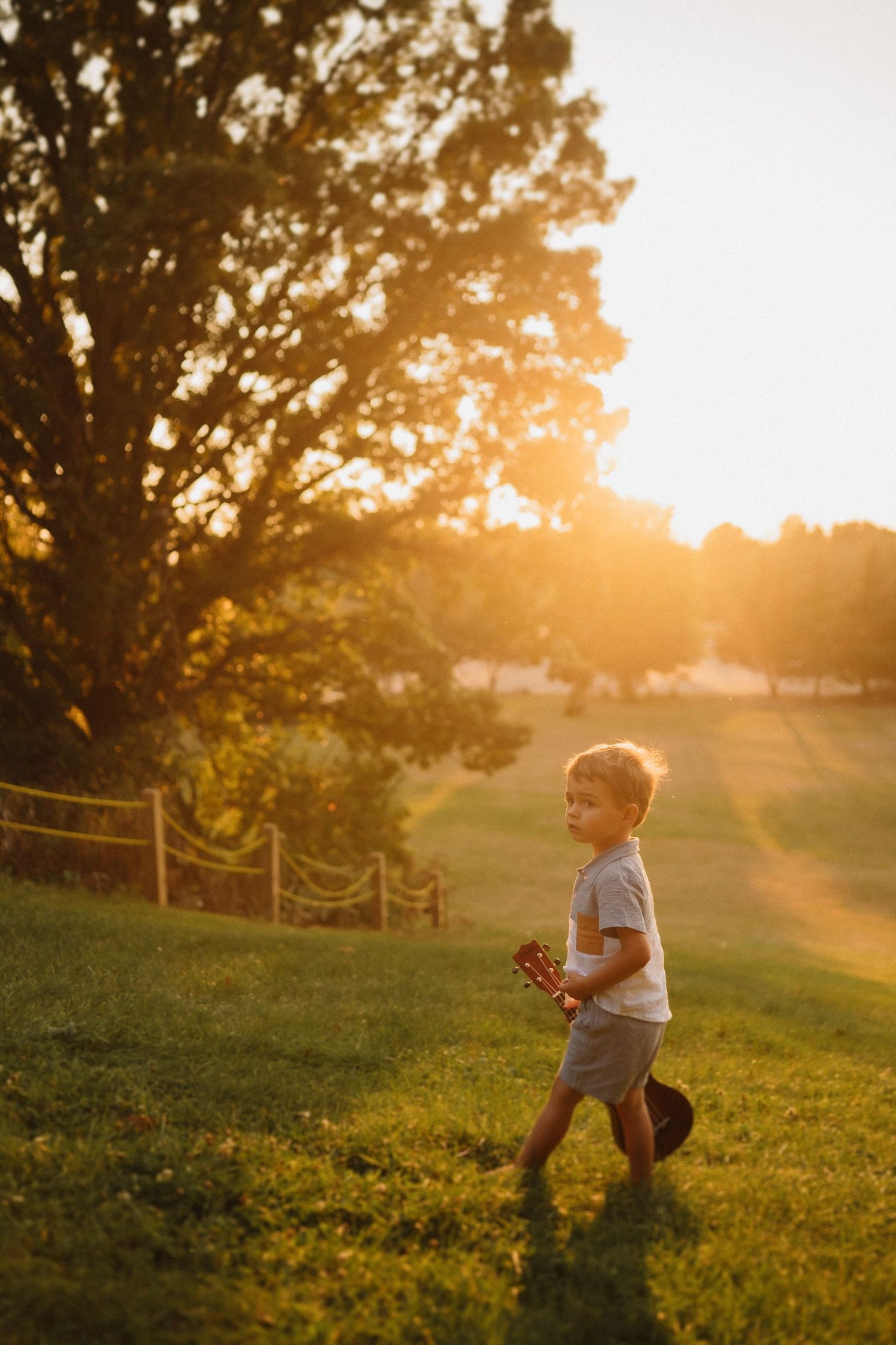 Young child playing in a grassy field during golden hour sunset.