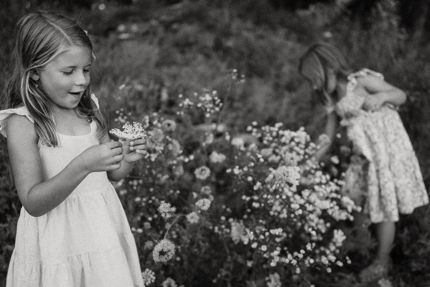Black and white photo of children playing among wildflowers in a garden.