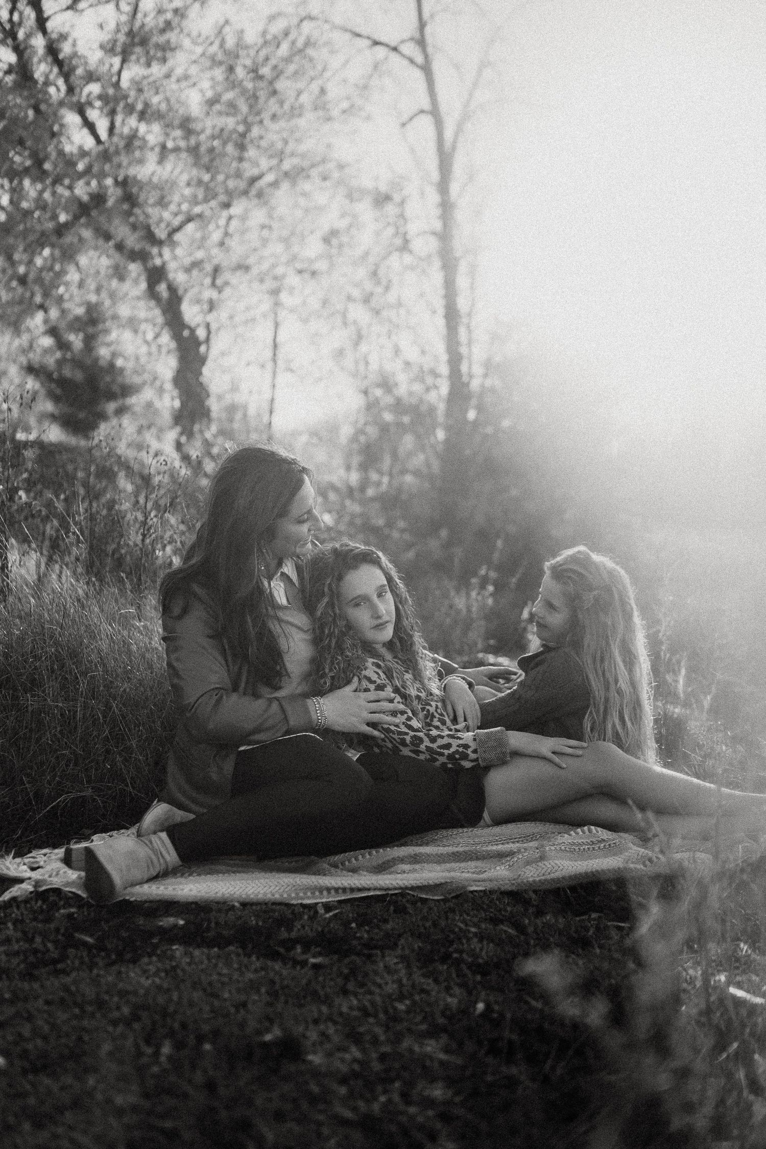 A couple relaxes together on a blanket in a dreamy black and white outdoor setting.
