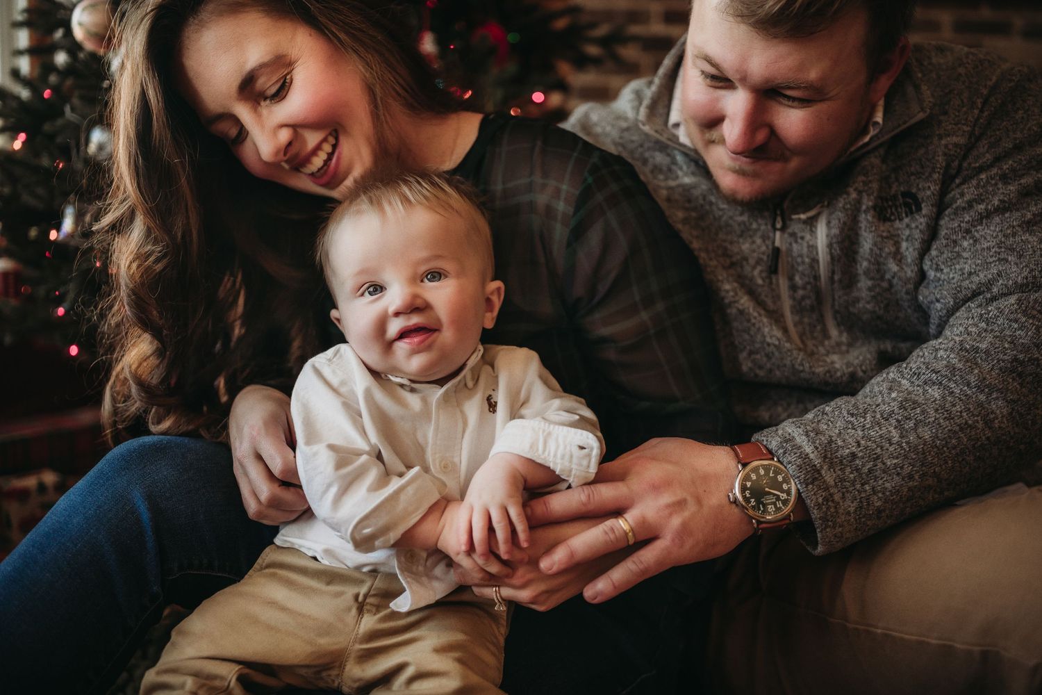 Family shares joyful moment together on couch during Christmas season.