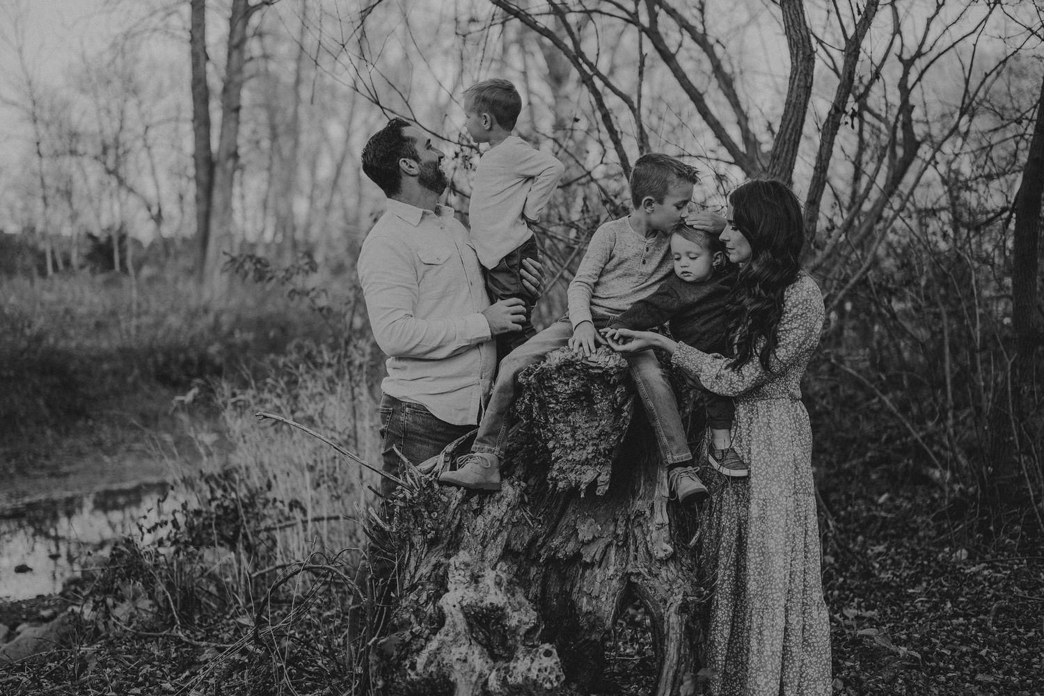 A black and white family portrait taken outdoors among trees and natural surroundings.