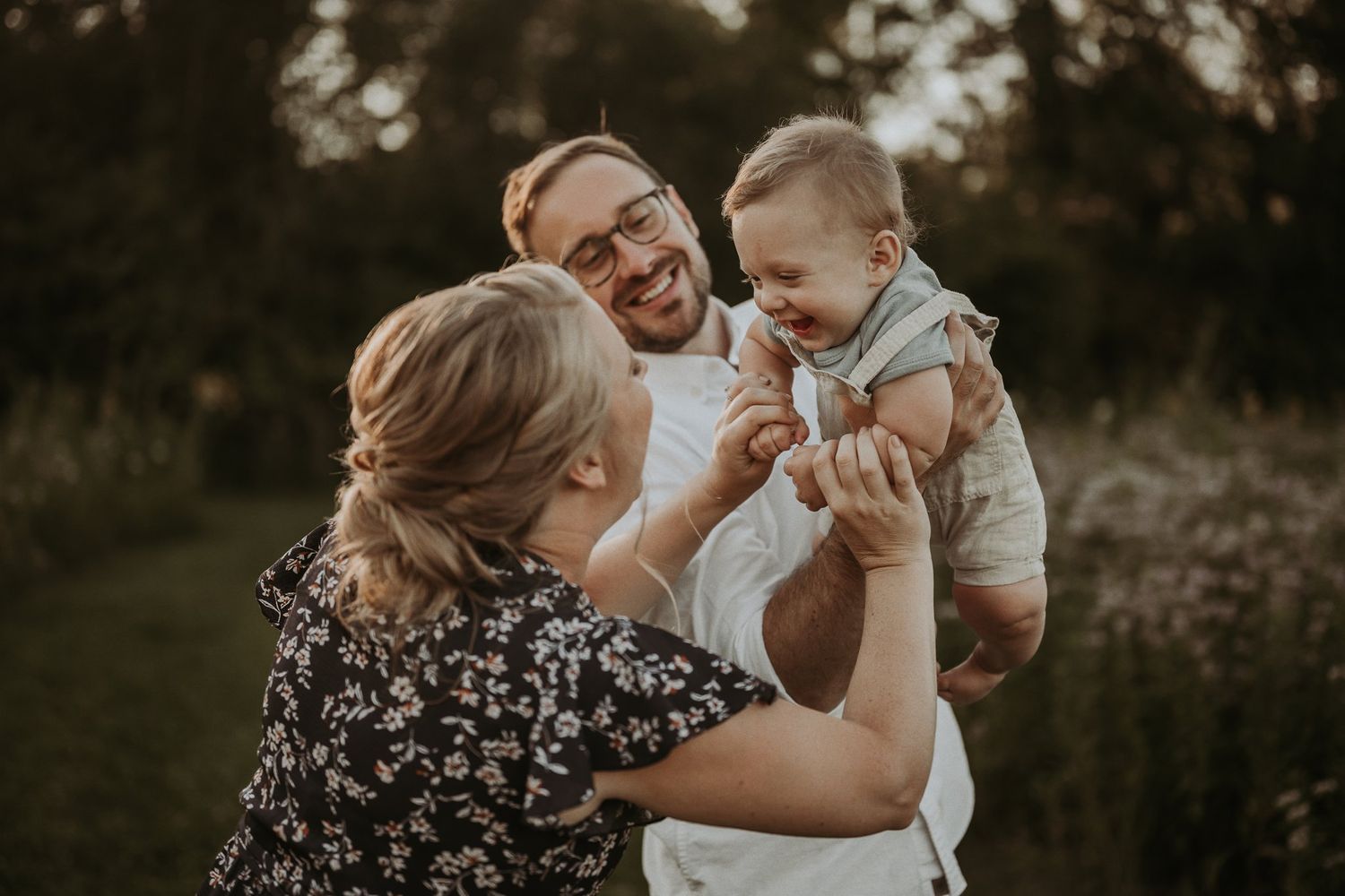 A happy family shares a playful moment together in a golden sunset field.
