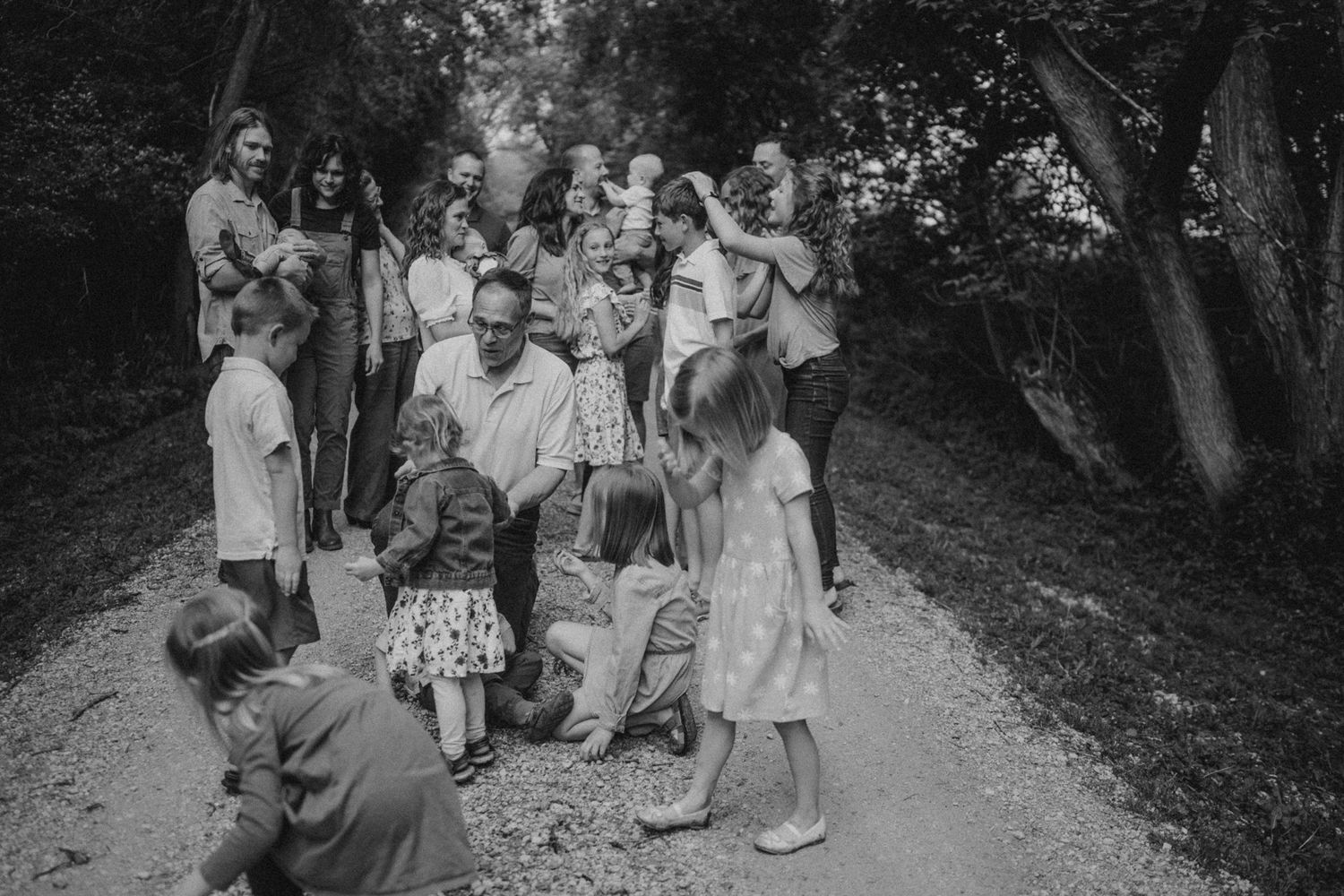 Large group of people gathered on a wooded path in black and white.