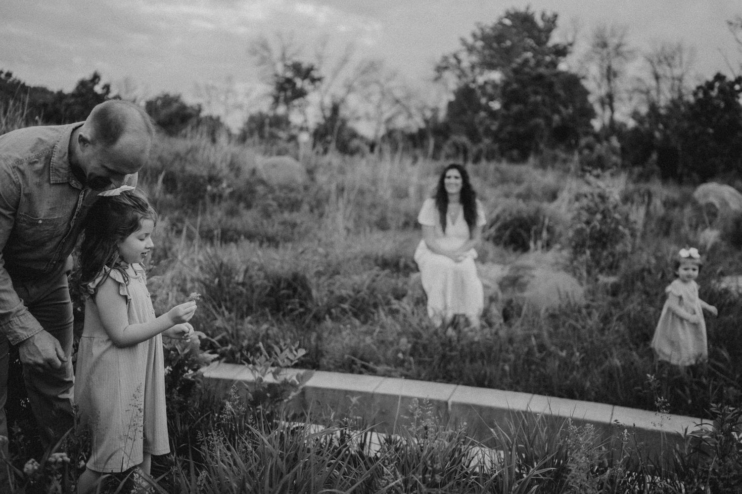 A black and white photograph of a family spending time together in a natural meadow setting.