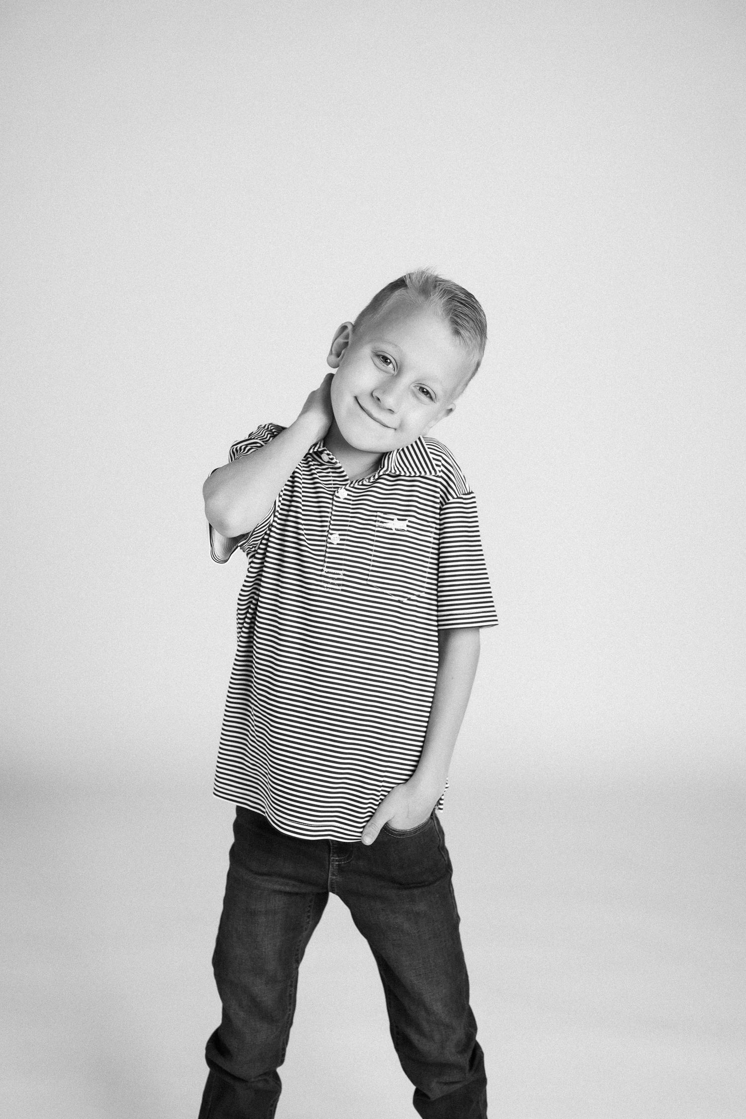 Black and white photo series of a young child in a striped polo shirt and dark pants making playful poses.