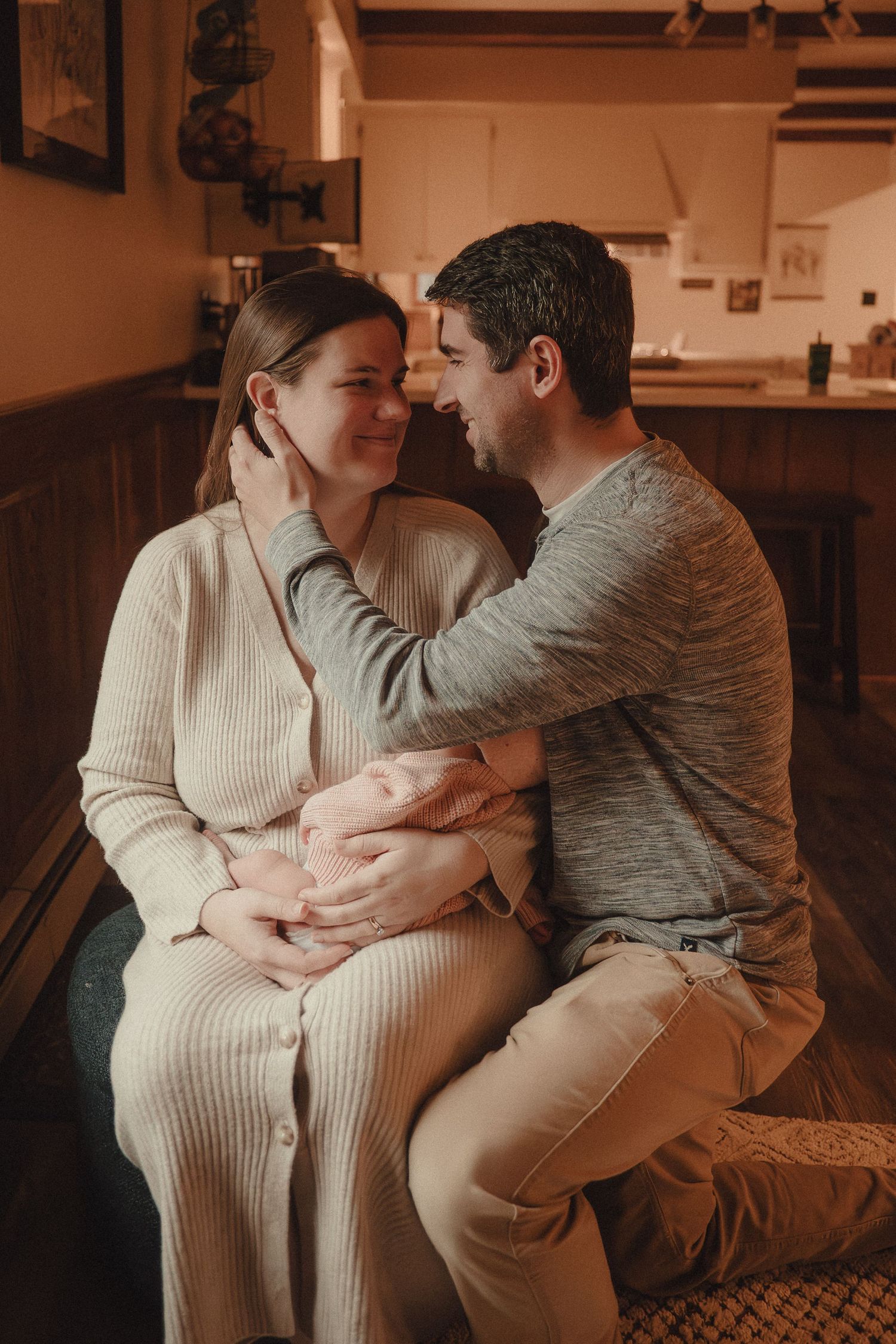 Couple sitting together on couch sharing intimate moment in warm lighting with person wearing cream sweater.