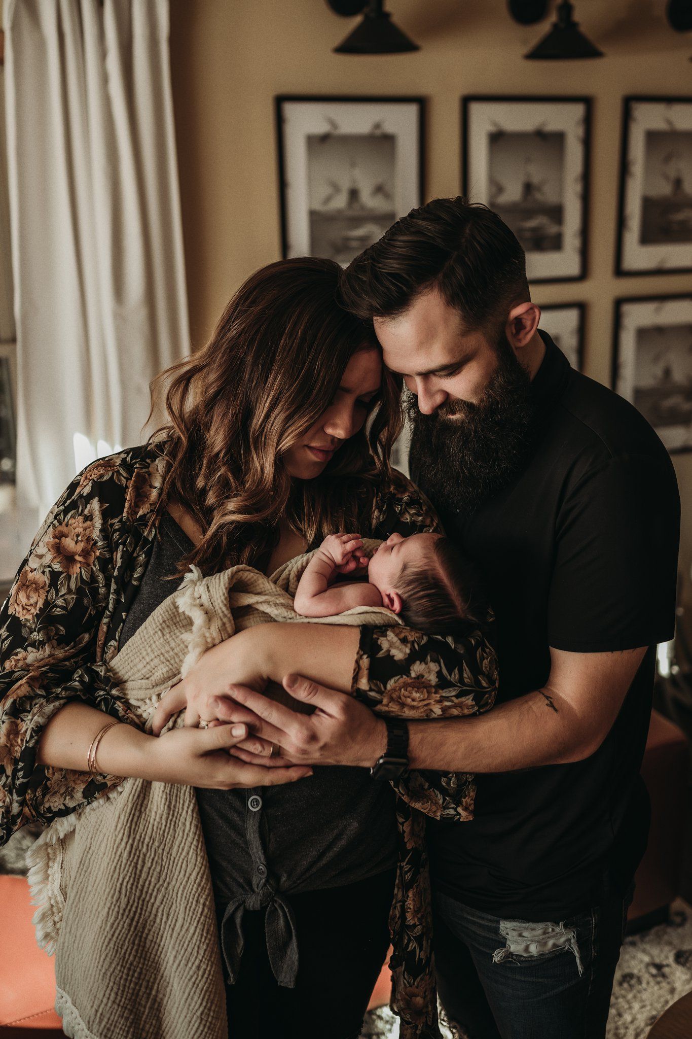 Parents gazing lovingly at newborn baby during intimate indoor photo session.