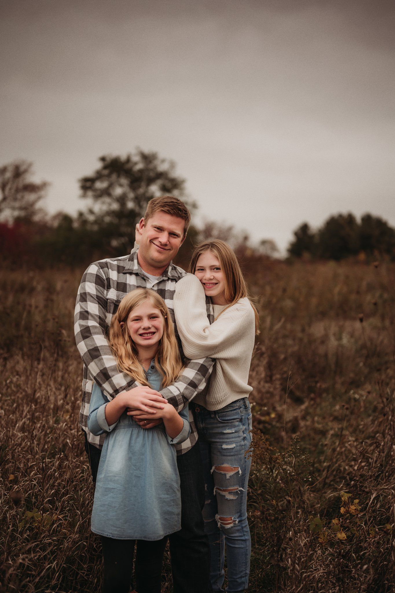 Candid outdoor family photoshoot in a golden autumn field with plaid and cream colored clothing.