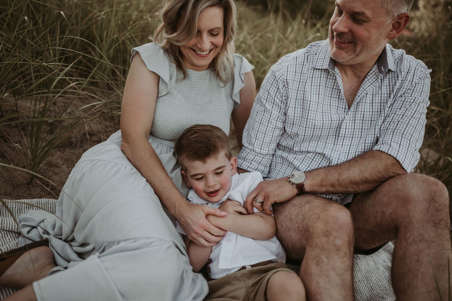 A family sits together on a blanket sharing an intimate moment outdoors.