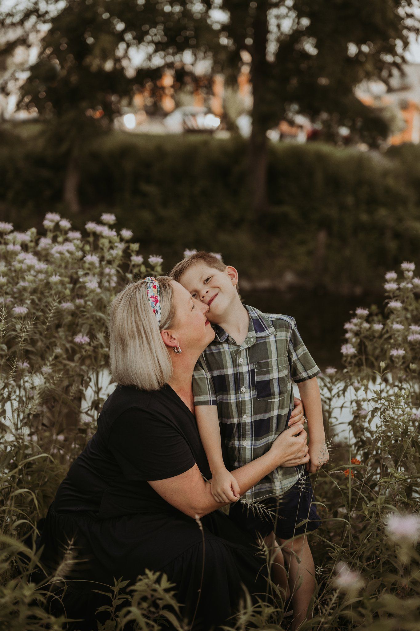 Tender moment between parent and child embracing in wildflower field at sunset.
