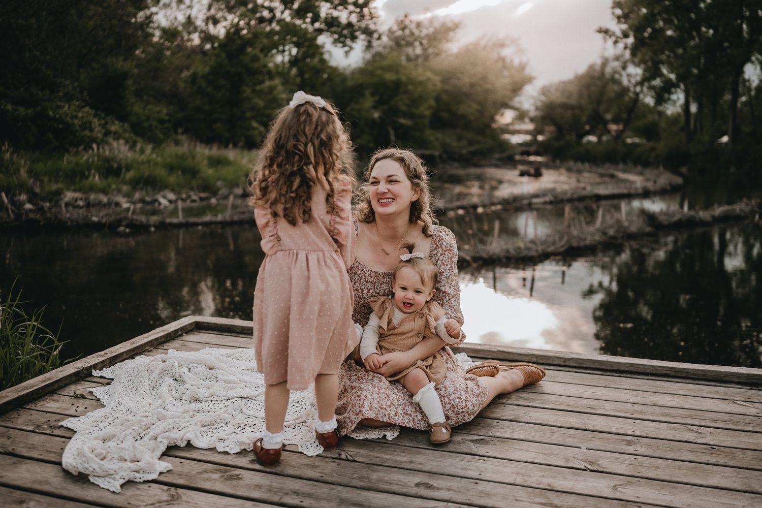 A candid family moment shared on a rustic wooden dock by the water.