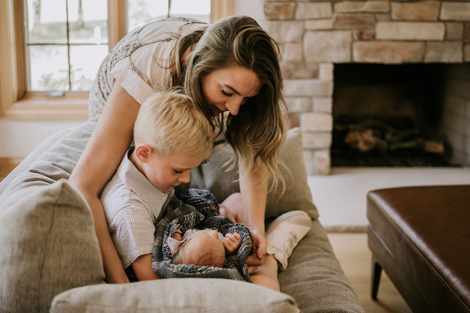 Family sharing a tender moment together on a cozy gray couch near a stone fireplace.
