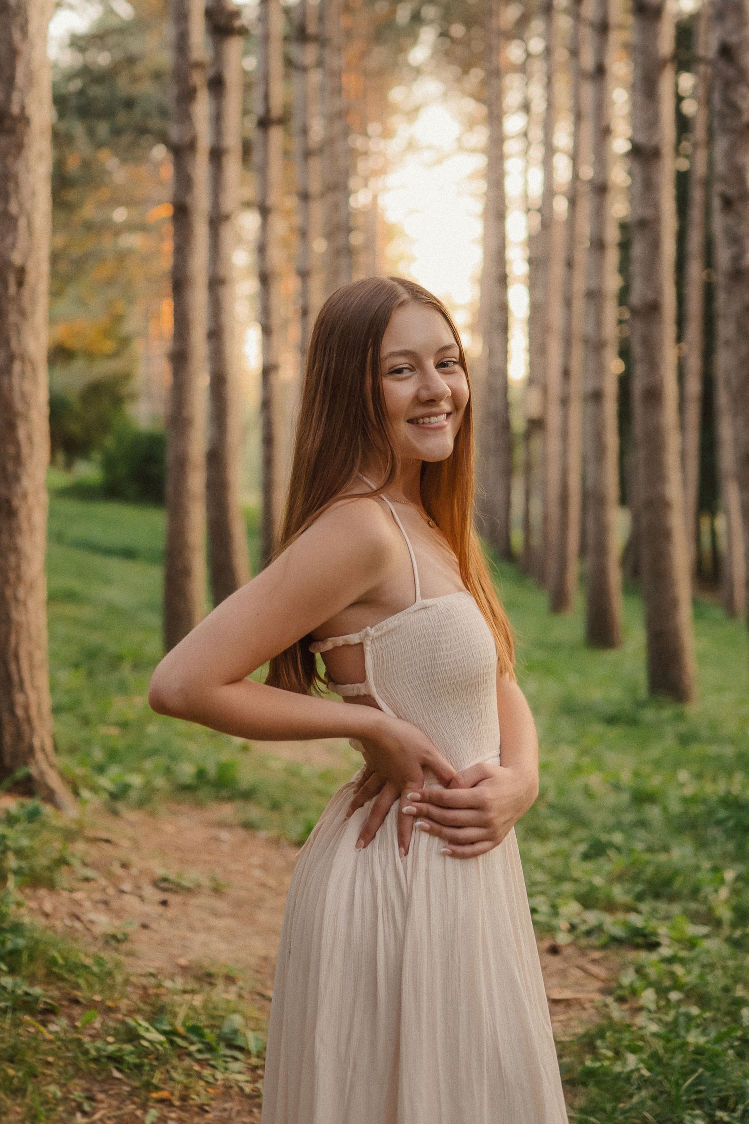 A series of four outdoor portrait poses in a sunlit pine forest with a light dress.
