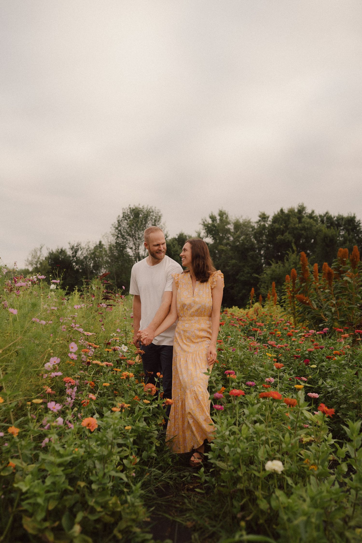 A couple shares an intimate moment together among vibrant wildflowers in a romantic garden setting.