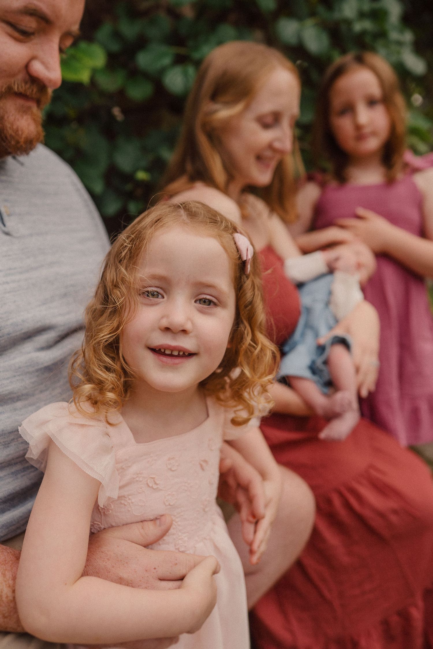 Multiple panels show a small child in a pink dress with curly hair in different candid poses during an outdoor photo session.