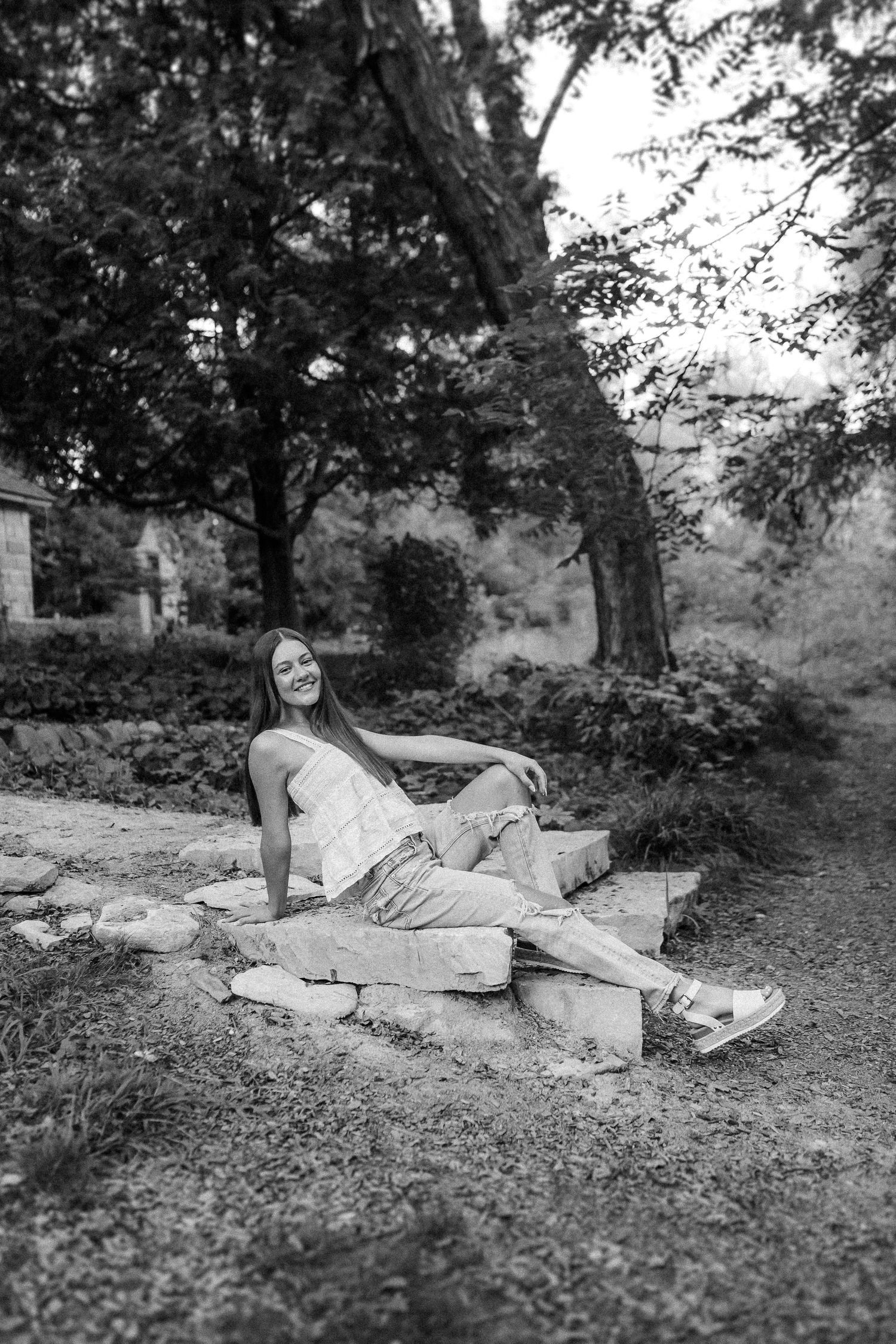 Black and white photo series of someone in white dress lounging on stone steps in a tranquil garden setting.