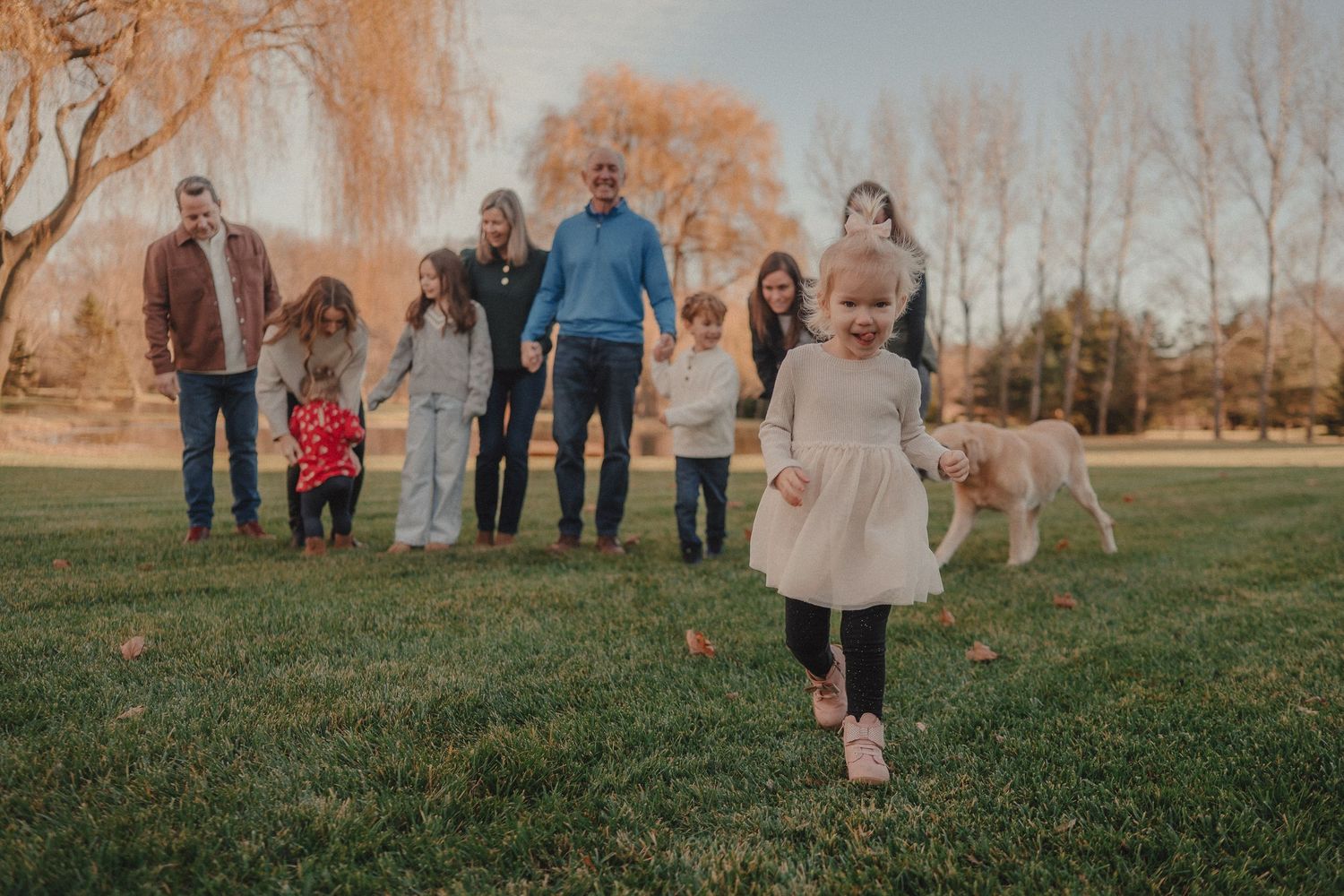 People gathered outdoors on a grassy hill during a fall afternoon.